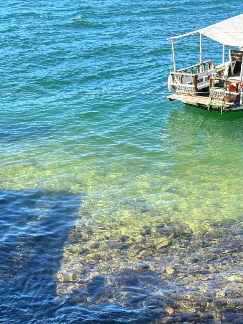 Barco em água cristalina em frente à casa